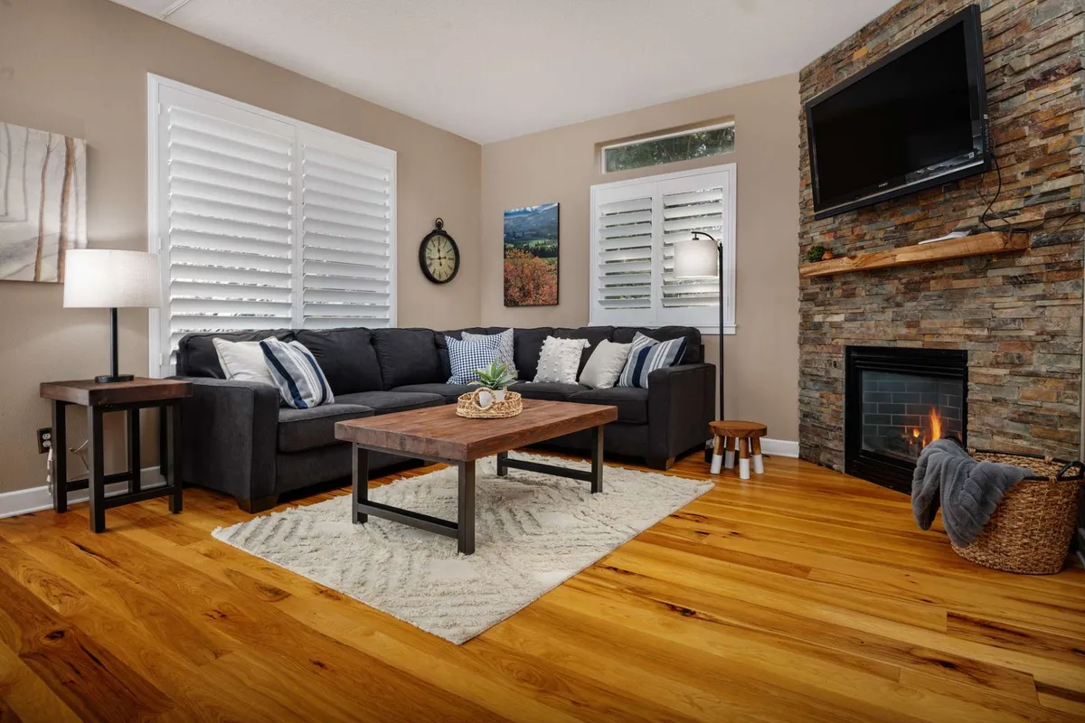 The image showcases a stylish and inviting living room with a plush sofa, a welcoming coffee table, a glowing fireplace, a prominent wall clock, and thoughtfully placed decorative items. The space exudes warmth and comfort, perfect for relaxing, gathering with loved ones, or enjoying quiet moments.