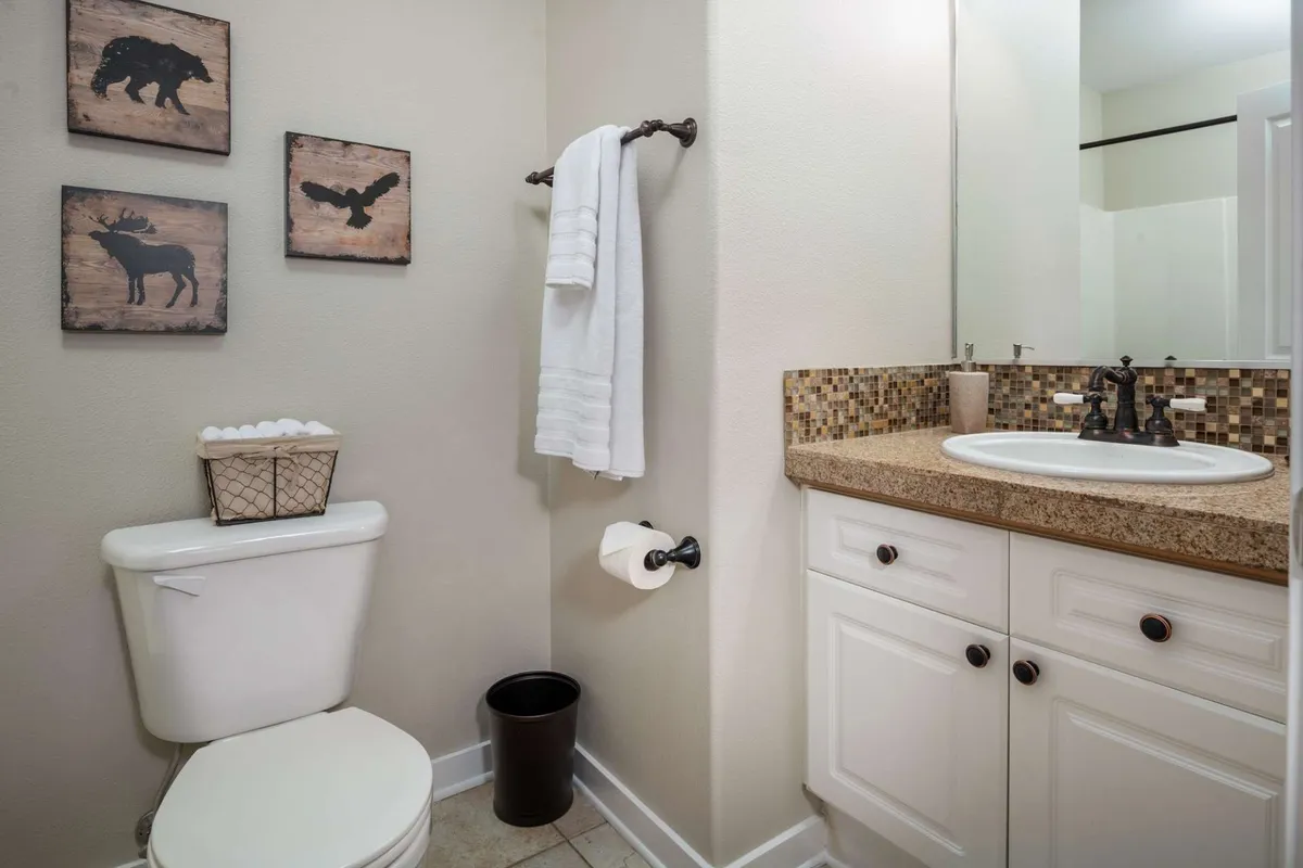 A bright, rustic bathroom with a granite countertop, crisp white towels, and charming wooden animal art adorning the walls. The space feels serene and clean, ideal for personal grooming and moments of self-care.