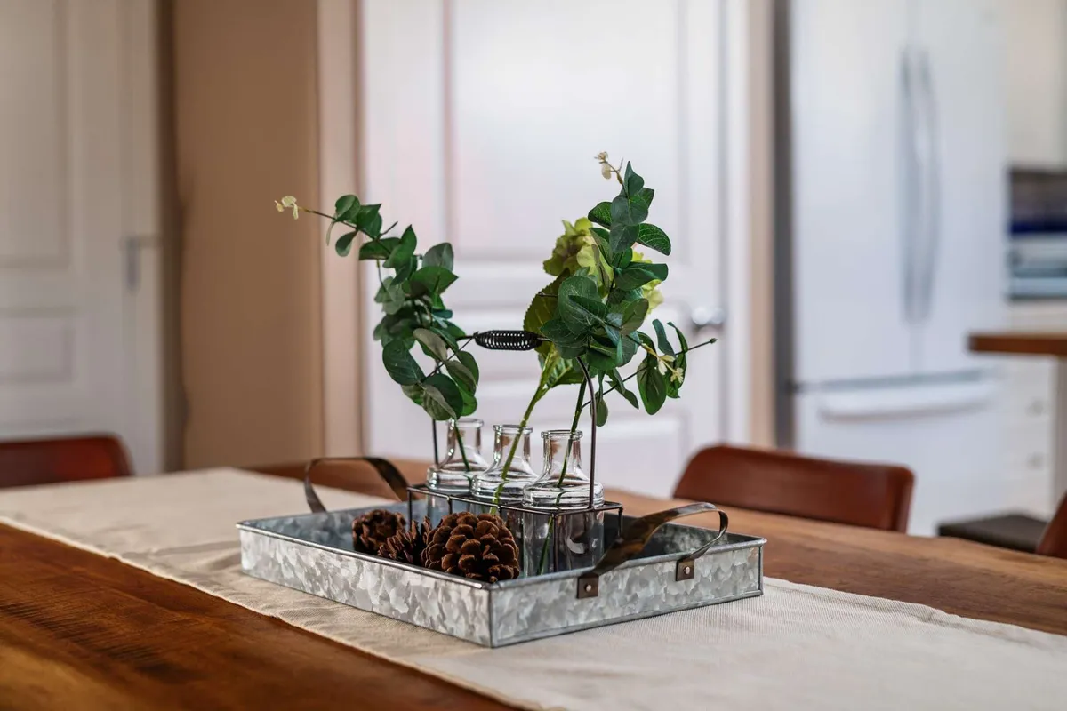A cozy dining table set with glass vases, greenery, and pinecones, perfect for family meals and gatherings. The arrangement evokes a sense of togetherness and warmth, tying back to family-centric amenities.