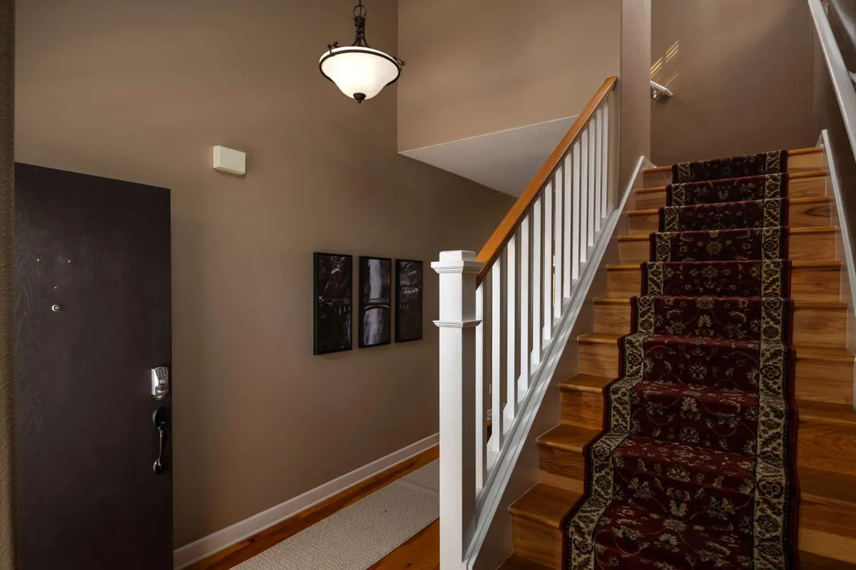 The image captures a welcoming entryway, featuring a staircase, doorway, and a light fixture. Wall art adds warmth to the entrance, creating an inviting transition into the home.